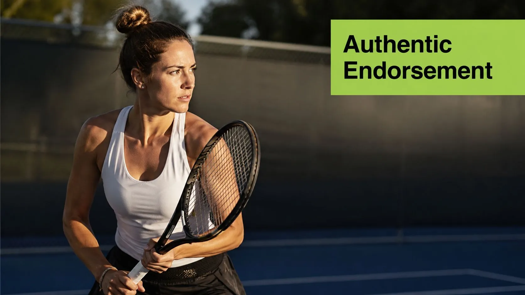 A professional female tennis player wearing a white tank top holding a tennis racket on a court.