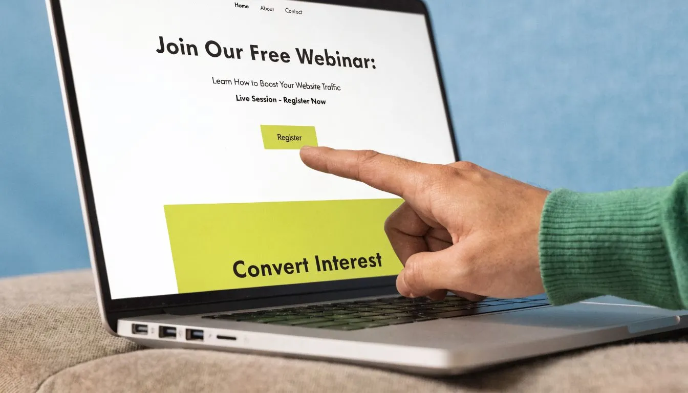A person points at the register button on a webinar sign up page displayed on a laptop screen.
